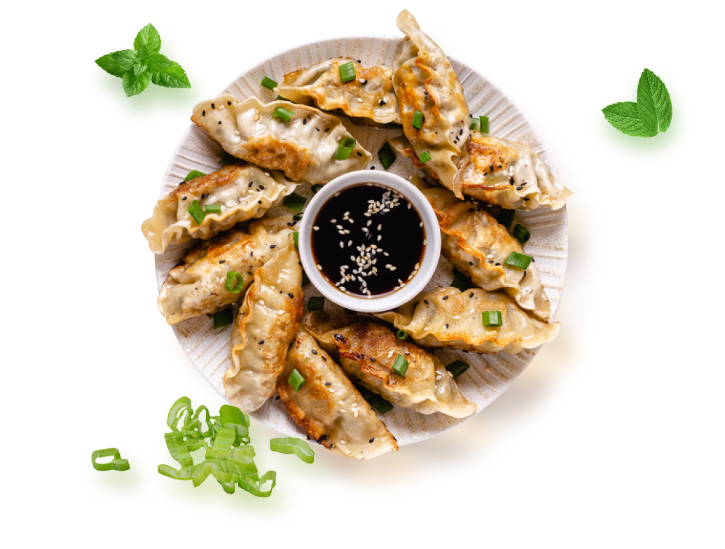 Plateau de gyozas vu du dessus avec sauce et herbes fraîches